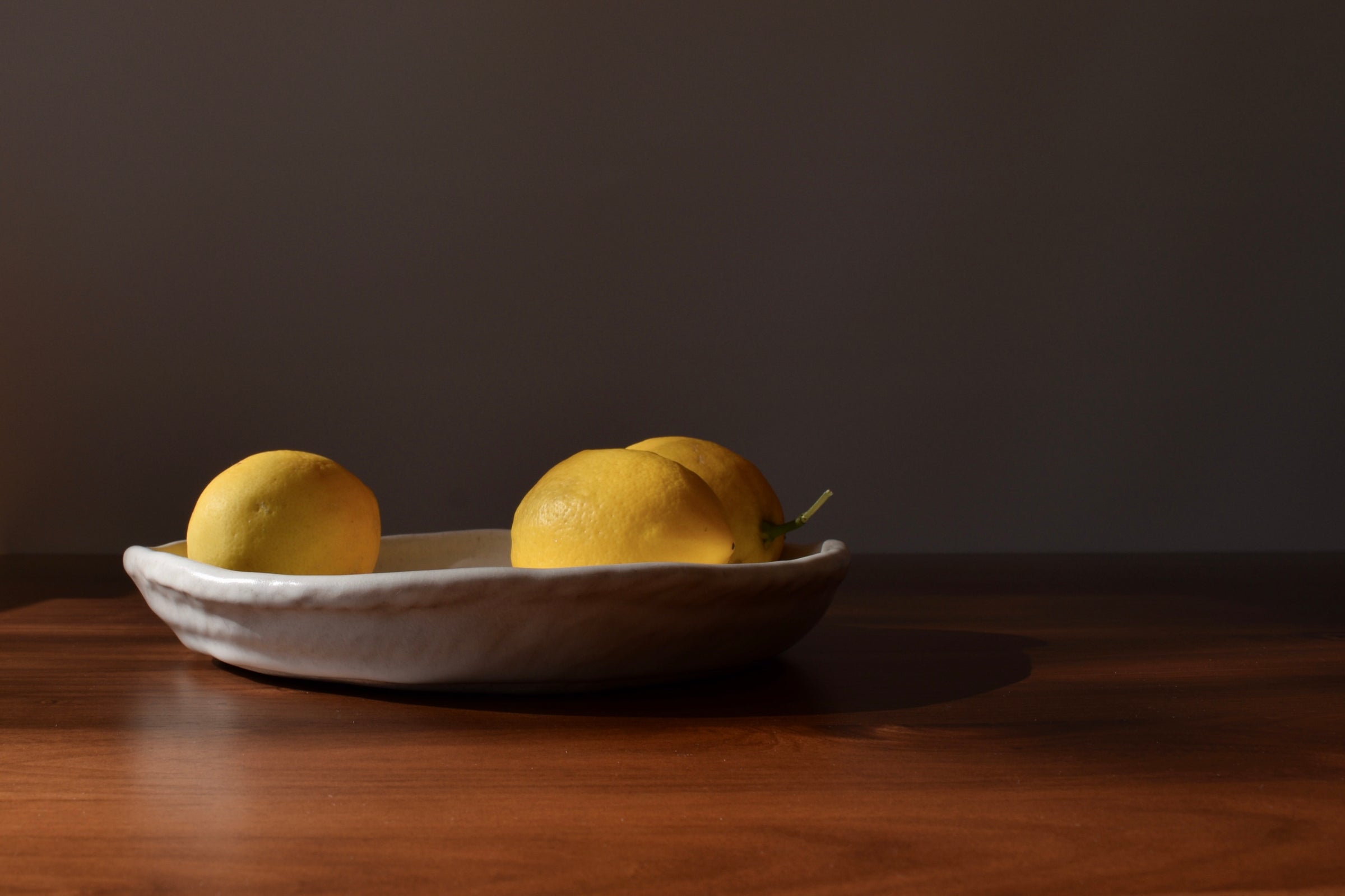 Two lemons on a white plate against a dark background